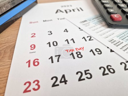 Téléchargez les photos : Tax payment day marked on a calendar - April 18, 2023 with 1040 form, financial concept - en image libre de droit