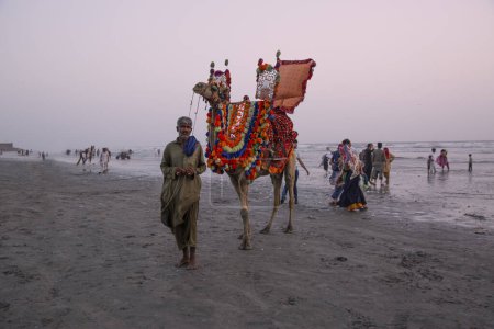 Foto de 23 Septiembre 2023, Karachi, Pakistán. Gente local con camello y turistas en Clifton Beach. La línea costera del mar Arábigo. - Imagen libre de derechos