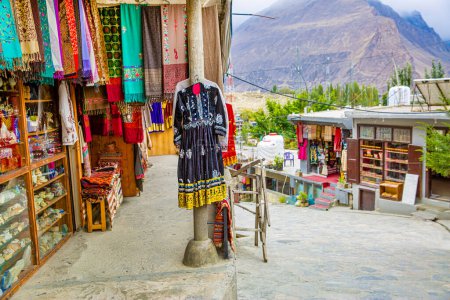 Street with shop with clothes and other souvenirs in Karimabad, Pakistan. Colorful scarfs and dresses. 
