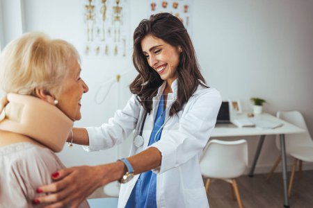 Photo for Portrait of a female doctor helping a senior woman at office with her neck injury and putting her collar a healthcare and medicine concepts. Doctor putting a neck brace on a senior patient - Royalty Free Image