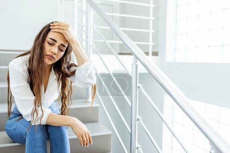 Téléchargez les photos : Jeune femme d'affaires déprimée et désespérée pleurant seule assise dans un escalier de rue souffrant de stress et de dépression victime de mafia ou licenciée perdant son emploi - en image libre de droit