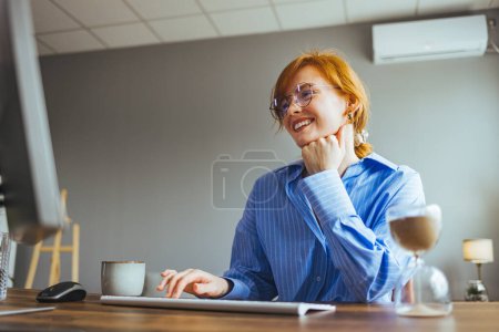 Téléchargez les photos : Jeune employée occupée à dactylographier un ordinateur écrire une lettre d'affaires au client - en image libre de droit