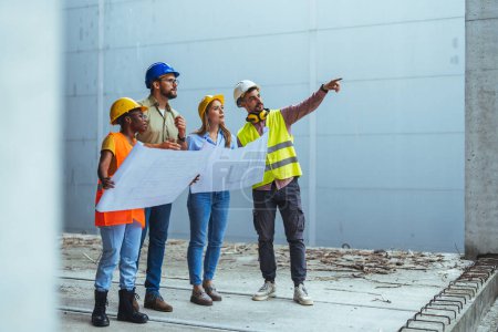 Photo for Happy engineering team with blueprint at the new building under construction, successful engineers teamwork working on site - Royalty Free Image