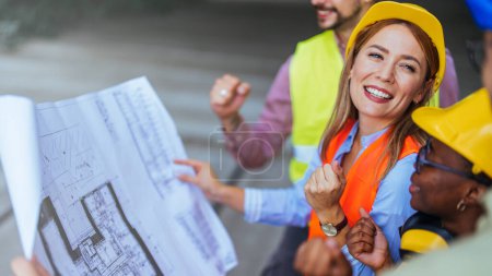 Photo for Group of successful engineers holding blueprint on construction site - Royalty Free Image