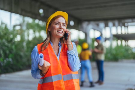 Photo for Caucasian female worker using smartphone on construction site - Royalty Free Image