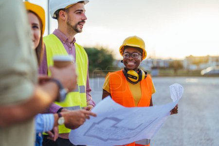 Photo for Group of engineers looking at a blueprint at construction site - Royalty Free Image