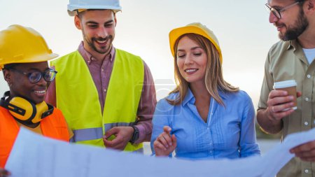 Photo for Group of engineers looking at a blueprint at construction site - Royalty Free Image