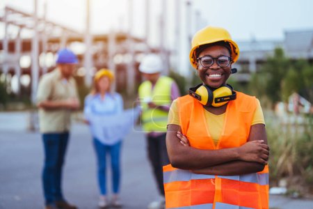Téléchargez les photos : Travailleur africain en casque et gilet orange sur le chantier de construction - en image libre de droit