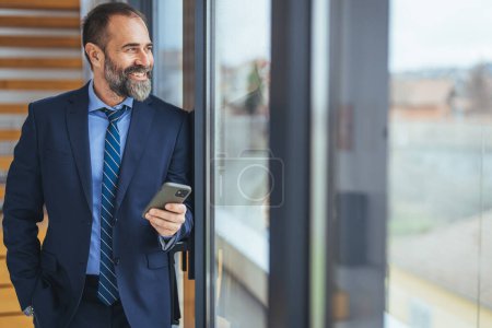 Photo for Shot of a young businessman using a smartphone in a modern office. Cropped shot of a mature designer texting on a cellphone in an office. Using the smartest tech to match his startup needs - Royalty Free Image