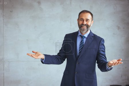 Photo for Cropped shot of executive Mature businessman wearing suit and tie while standing at isolated grey background. Copy space. Businessman looking at the camera while standing alone in a modern workplace. - Royalty Free Image