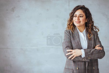 Photo for Portrait of young smiling woman looking at camera with crossed arms. Happy girl standing in creative office. Successful businesswoman standing in office with copy space. - Royalty Free Image