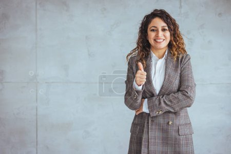 Téléchargez les photos : Jeune femme confiante debout avec les bras croisés sur le mur gris. Portrait de femme d'affaires souriante aux bras croisés isolés sur fond gris avec espace de copie. - en image libre de droit