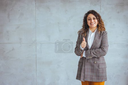 Foto de Retrato recortado de una atractiva joven empresaria parada sola en su oficina con los brazos cruzados durante el día. Retrato de una mujer de negocios de pie en una oficina moderna - Imagen libre de derechos
