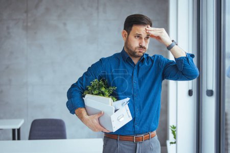 Photo for Unemployed guy in formal wear holding personal belongings, feeling depressed after losing his job. Upset Eastern man with cardboard box of things leaving office after being fired - Royalty Free Image