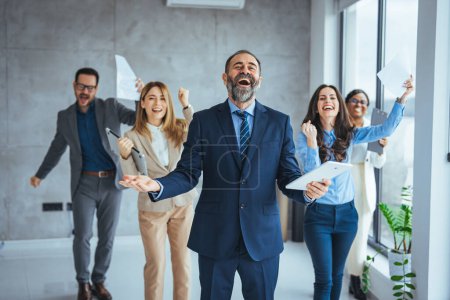 Photo for Shot of office staff celebrating a win. Success and team work concept. Group of business partners with raised up hands in light modern workstation, celebrating the breakthrough in their company - Royalty Free Image