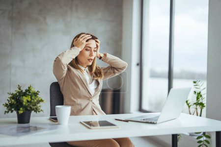 Photo for Shot of a young businesswoman looking stressed out while working in an office. Stressed business woman working from on laptop looking worried, tired and overwhelmed - Royalty Free Image