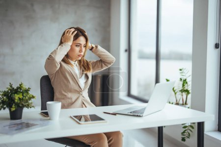 Photo for Shot of a young woman suffering from stress while using a computer at her work desk. Female entrepreneur with headache sitting at desk. The stress and tension are becoming too much to handle - Royalty Free Image