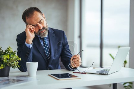 Photo for Stressed man in office looking on documents. Business man in office. Business man having problem at work. Tired man feel pain eyestrain holding glasses rubbing dry irritated eyes fatigued from computer work, stressed - Royalty Free Image