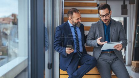 Téléchargez les photos : Prise de vue de deux jeunes gens d'affaires heureux qui aiment travailler sur une tablette PC. Partager des idées lors d'une réunion dans un studio de bureau moderne. Collaborations fructueuses - en image libre de droit