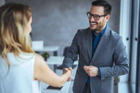 Photo for Business people shaking hands after successful meeting. Businessman And Businesswoman Shaking Hands In Office. Businessman shaking hands with his female partner celebrating successful teamwork. - Royalty Free Image
