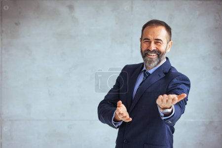 Téléchargez les photos : Portrait d'homme d'affaires mature heureux regardant la caméra. Homme satisfait multiethnique avec barbe se sentant confiant au bureau. Homme d'affaires prospère du Moyen-Orient souriant dans un bureau créatif - en image libre de droit