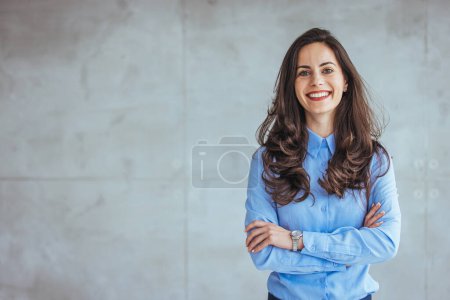 Photo for Shot of a confident young businesswoman standing in a modern office. Portrait of middle aged businesswoman in modern office looking at camera. Confident business woman with arms crossed standing - Royalty Free Image