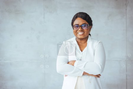 Photo for Studio portrait of happy successful confident black business woman. Beautiful young lady in white jacket smiling at camera standing isolated on blank solid gray colour copyspace background - Royalty Free Image