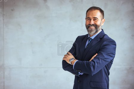 Porträt eines selbstbewussten Geschäftsmannes, der in einem modernen Büro arbeitet. Reifer, fröhlicher Geschäftsmann am Arbeitsplatz. Porträt eines lächelnden ceo am modernen Büroarbeitsplatz im Anzug 