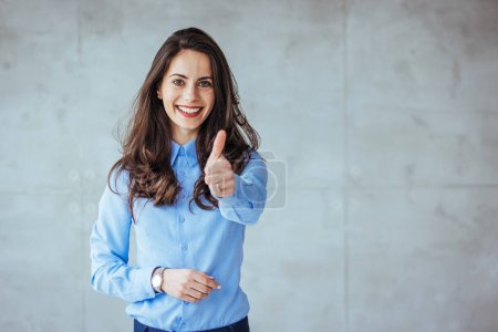 Photo for Young happy cheerful woman showing thumb up. Positive caucasian young girl woman showing thumb up looking at camera, checking for good quality recommendation isolated in grey background. Well done! Great job! - Royalty Free Image