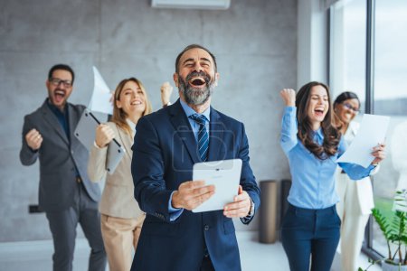 Photo for Shot of office staff celebrating a win. Success and team work concept. Group of business partners with raised up hands in light modern workstation, celebrating the breakthrough in their company - Royalty Free Image