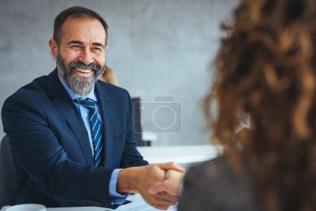 Photo for Happy senior entrepreneur came to an agreement with his colleague on a meeting in the office. Happy businessmen on a job interview in the office. Focus is on mature businessman shaking hands with a candidate. - Royalty Free Image