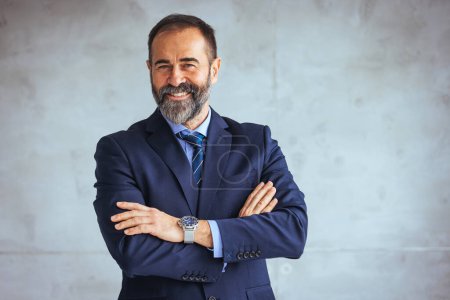 Photo for Mature businessman portrait. Successful businessman posing with crossed arms and smiling at camera. Good-looking middle-aged businessman with arms crossed isolated in gray background - Royalty Free Image