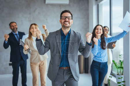 Photo for Hot of a group of young businesspeople standing together and clapping in a modern office. Shot of colleagues celebrating during a meeting in a modern office. Nothing motivates productivity like team morale - Royalty Free Image