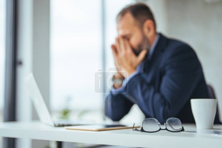 Photo for Stressed man in office looking on documents. Business man in office. Business man having problem at work. Tired man feel pain eyestrain holding glasses rubbing dry irritated eyes fatigued from computer work, stressed - Royalty Free Image