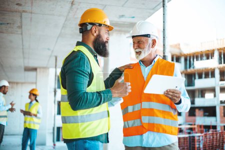 Téléchargez les photos : Deux ingénieurs parlent pendant qu'ils travaillent sur le chantier - en image libre de droit