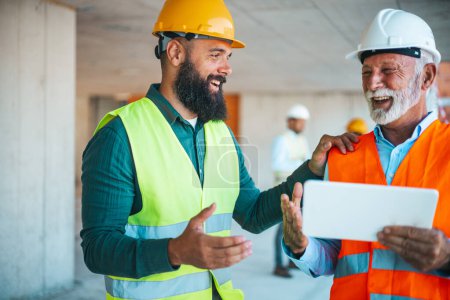 Téléchargez les photos : Deux ingénieurs parlent pendant qu'ils travaillent sur le chantier - en image libre de droit
