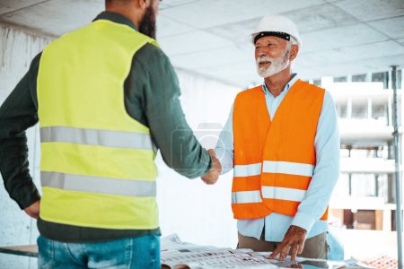 Photo for Male engineers or architects handshaking at construction site - Royalty Free Image