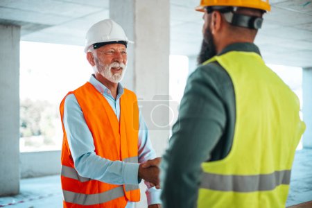 Foto de Ingenieros masculinos o arquitectos apretón de manos en el sitio de construcción - Imagen libre de derechos