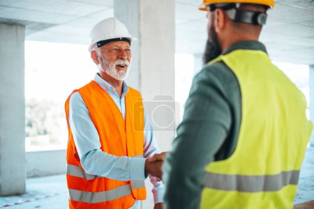 Foto de Ingenieros masculinos o arquitectos apretón de manos en el sitio de construcción - Imagen libre de derechos