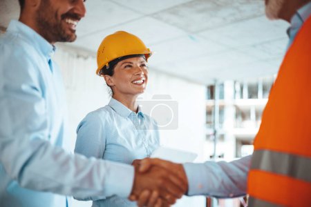 Photo for Woman architect or engineer looking at male colleagues handshaking at construction site - Royalty Free Image