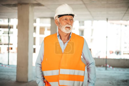 Photo for A senior construction site manager visually inspects a building project. Shot of a senior male foreman. A smiling, senior worker with a helmet takes a break from work. A senior worker - Royalty Free Image