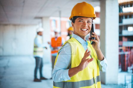 Photo for Shot of a young engineer using a smartphone in an industrial place of work. Architect is using mobile phone on construction site. She is focused on her work. Construction woman closing deal on the phone. - Royalty Free Image