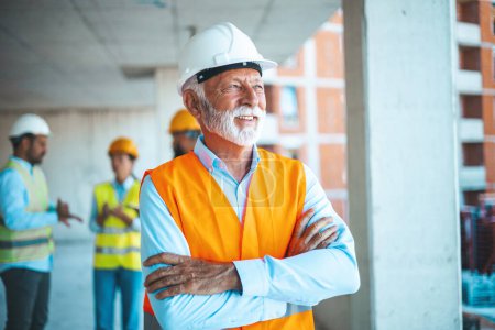 Photo for Visiting construction site. Portrait of confident elderly construction engineer in classic suit and hardhat is holding digital tablet and looking at camera while visiting building object - Royalty Free Image