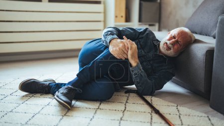 Photo for Elderly Senior Man Slip And Fall. Fallen Old Person in the Living Room.  Senior man falling down on carpet and lying on the floor in living room at home, Falls of older adults concept - Royalty Free Image