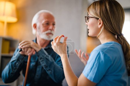Photo for Woman doctor consult prescribe medicines to old male patient at home. Female GP hold bottles pills give prescription medication to mature client on therapy. Elderly healthcare concept. - Royalty Free Image