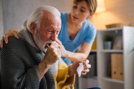 Photo for Nice senior bearded man taking a paper tissue, sick at home. Female caregiver helping senior man. Female professional doctor touching shoulder comforting upset senior patient. - Royalty Free Image