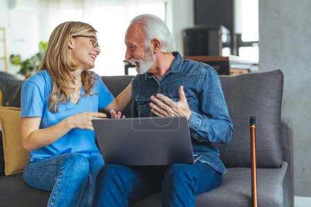 Photo for Nursing home, caregiving and elderly people assistance service. Friendly smiling nurse showing good analysis result or help with online call on laptop to old senior man patient - Royalty Free Image
