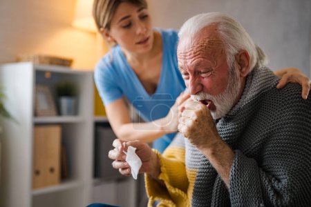 Photo for Doctor consoling senior patient at home. Old people senior man with winter seasonal illness fever cold problems. Concept of mature retired with disease. Front view of senior man coughing - Royalty Free Image