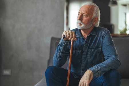 Photo for Grey hair man with disabled stick sitting on sofa and thinking at home - Royalty Free Image