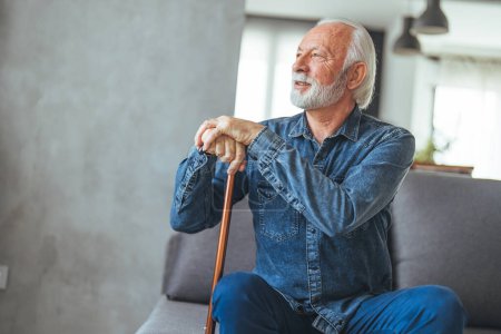 Photo for Senior man with disabled stick sitting on sofa at home - Royalty Free Image